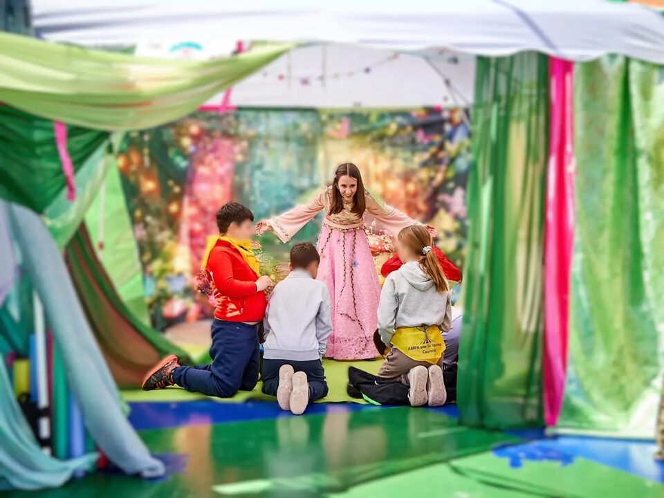 Niños participando con un personaje de hada dentro de una carpa inmersiva de YUCAX