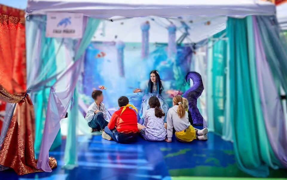 Niños participando en una experiencia inmersiva dentro de una carpa ambientada como un mundo submarino